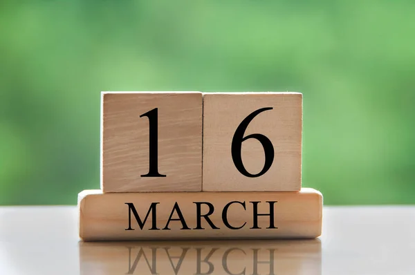 March 16 calendar date text on wooden blocks with blurred park background. Copy space and calendar concept.