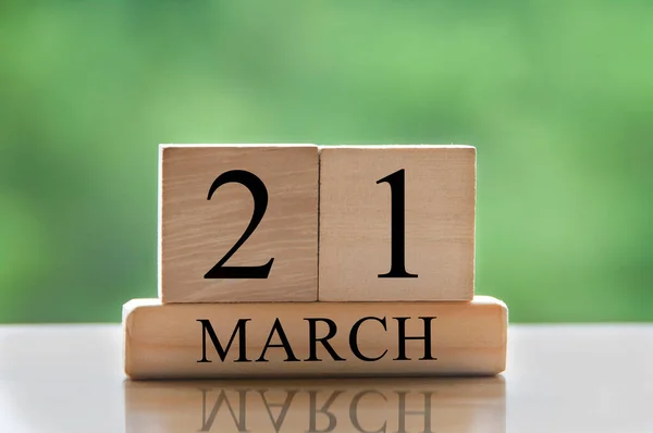 March 21 calendar date text on wooden blocks with blurred park background. Copy space and calendar concept.