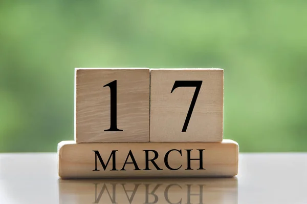 March 17 calendar date text on wooden blocks with blurred park background. Copy space and calendar concept.