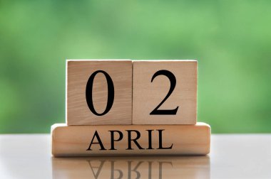 April 2 calendar date text on wooden blocks with blurred park background. Copy space and calendar concept.