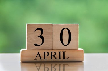 April 30 calendar date text on wooden blocks with blurred park background. Copy space and calendar concept.