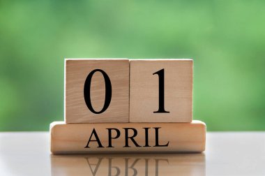 April 1 calendar date text on wooden blocks with blurred park background. Copy space and calendar concept.