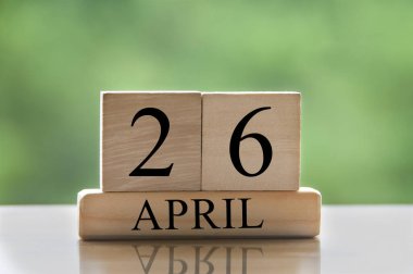 April 26 calendar date text on wooden blocks with blurred park background. Copy space and calendar concept.