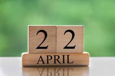 April 22 calendar date text on wooden blocks with blurred park background. Copy space and calendar concept.