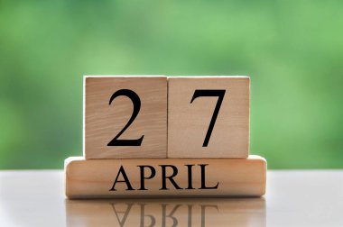 April 27 calendar date text on wooden blocks with blurred park background. Copy space and calendar concept.