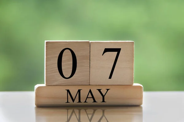 May 7 calendar date text on wooden blocks with blurred nature background. Copy space and calendar concept.