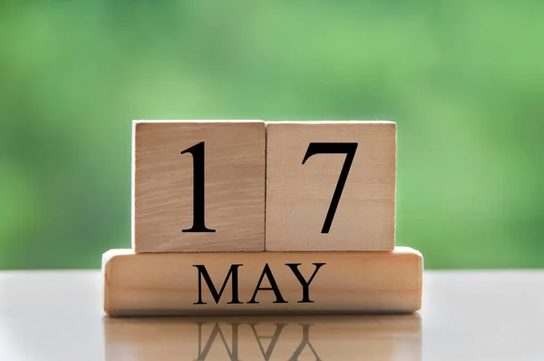 May 17 calendar date text on wooden blocks with blurred nature background. Copy space and calendar concept.