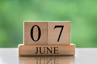 June 7 calendar date text on wooden blocks with blurred nature background. Copy space and calendar concept.