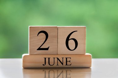 June 26 calendar date text on wooden blocks with blurred nature background. Copy space and calendar concept.