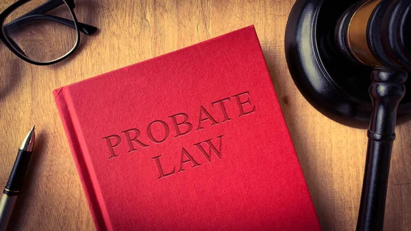 Probate law book on wooden table surrounded with gavel, glasses and pen. Law concept.