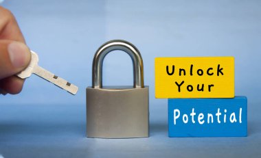 Unlock your potential text wooden blocks with hand holding key. Motivational concept.