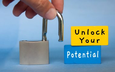 Unlock your potential text wooden blocks with hand holding padlock. Motivational concept.