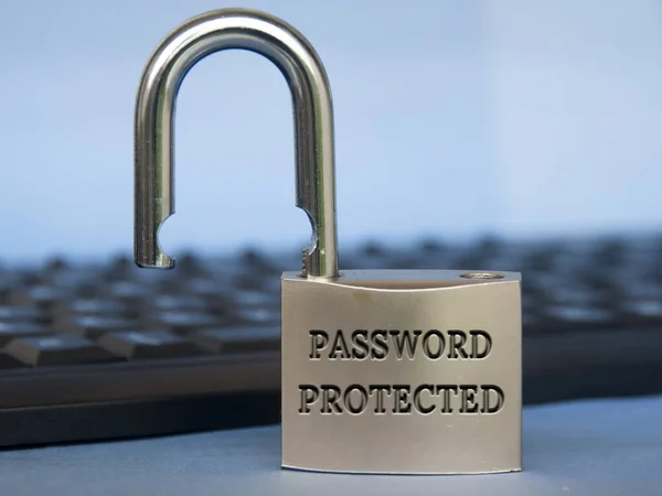 Password protected text engraved on padlock with blurred keyboard background. Password security concept.