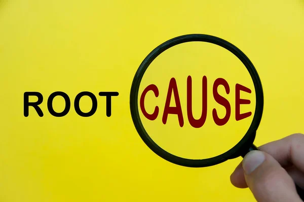 Close-up at root cause text through magnifying glass on yellow cover background. Root cause analysis concept.