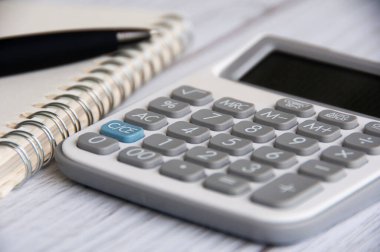 Close up of calculation with blurred background of notebook and pen. Copy space and business concept.
