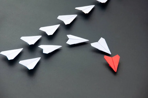 Red paper plane origami leading white planes on dark background. Leadership skills concept.