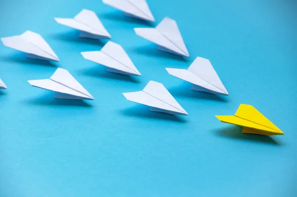 Yellow paper plane origami leading white planes on blue background. Leadership skills concept.