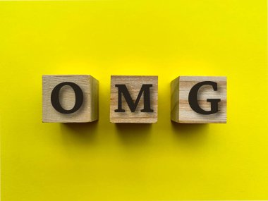 Tahta bloklardaki sarı arkaplanlı OMG alfabesi. Kavramsal