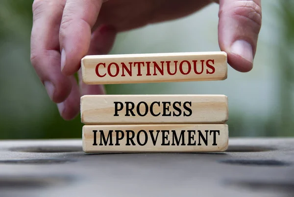 Continuous process improvement text on wooden blocks with blurred nature background. Process improvement and business concept.