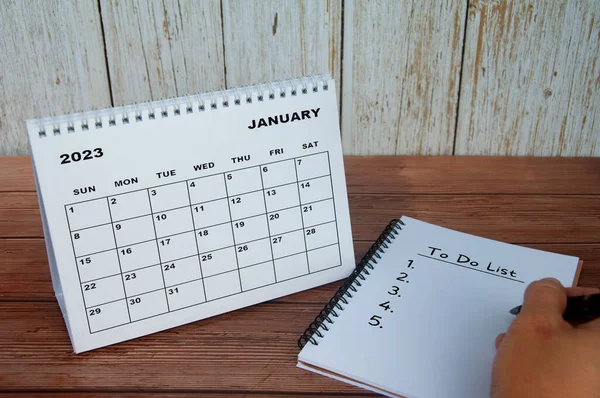 January 2023 white desk calendar with notebook with text - to do list. Calendar and to do list concept.