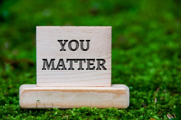 You matter text on wooden block with green nature background. Motivational concept.