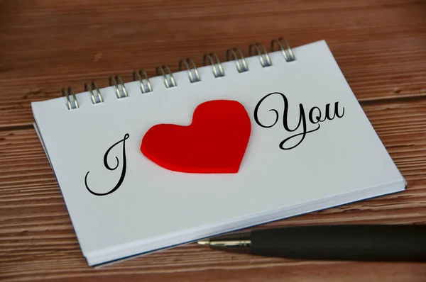 I love you text on notepad with wooden cover and pen background. Romance and relationship concept.