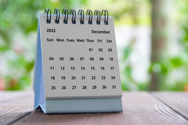 December 2022 table calendar with blurred nature background. Year end concept.