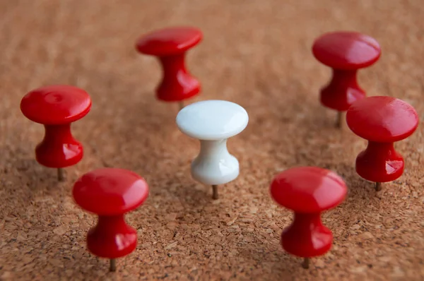 White push pin surrounded by red push pins. Harassment and discrimination concept.