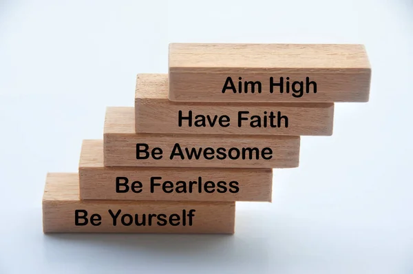 Words of motivation on wooden blocks - Aim high, have faith, be awesome, be fearless, be yourself.