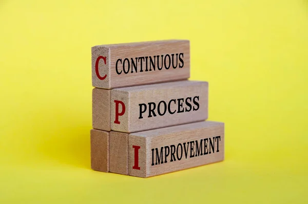 Continuous process improvement text on wooden blocks with yellow background. Business improvement and process standardization concept.