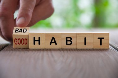 Finger turning bad and good text on wooden blocks. Good and bad habit concept. clipart