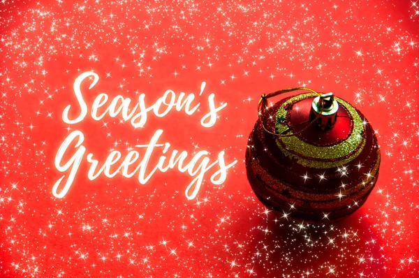 Season\'s greetings wishes with Christmas ball and shining stars background. Christmas celebration concept.