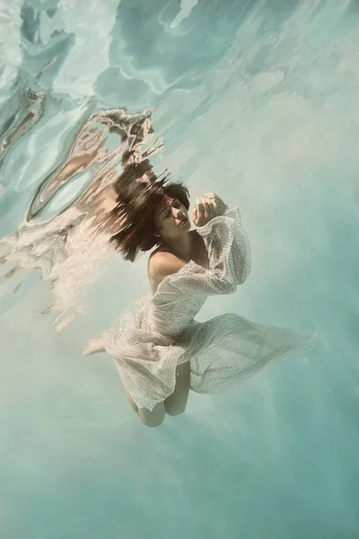 Una Chica Vestido Azul Nada Bajo Agua Sobre Fondo Claro — Foto de Stock