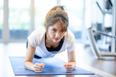 Asyalı kadın portresi spor salonunda kalas egzersizi yapıyor. 