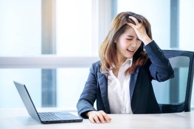 Asyalı güzel bir kadının modern ofis odasında dizüstü bilgisayarla düşünmesi stresli bir iş.