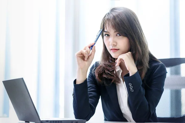 在现代写字楼里 工作着漂亮的亚洲女人 用笔记本电脑思考着自己的工作压力 — 图库照片