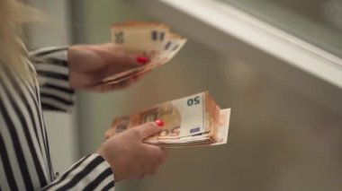 Zenginlik, aile bütçesi, çevrimiçi ticaret ve çevrimiçi ticaret kavramları gibi beyaz bir zemin üzerinden banknotlar sayan zengin bir kadın. Çok para kazanma kavramı. Avro say, para say.