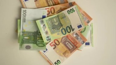 Euro banknotları beyaz masaya atılır. Zenginlik konsepti, aile bütçesi, online ticaret ve online ticaret. Çok para kazanma kavramı. İki eli olan kadın, tüm parayı alır.