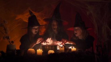 Cadı kılığına girmiş üç genç kız kazanın üzerinde sihirbazlık yapıyor ve büyü yapıyorlar. Cadılar Bayramı dehşeti. Korkunç bir hikaye. Gece Masalı.
