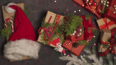 Dekoratif bir masada hediyeler dönüyor. Yanında Noel Baba şapkası var. Reklam için yer var. Metin için yer.