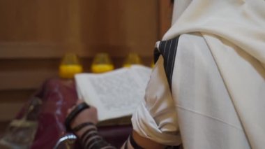 Sinagogda bir Yahudi dua ediyor. Bir adam başkanlığın yanında duruyor ve bir kitap okuyor. Arka plan