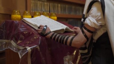Sinagogda bir Yahudi dua ediyor. Bir adam başkanlığın yanında duruyor ve bir kitap okuyor. Kamera gittikçe yaklaşıyor..