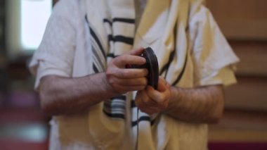 Yetişkin bir adam, Yahudi, tefillin katlıyor. Yakın plan el.