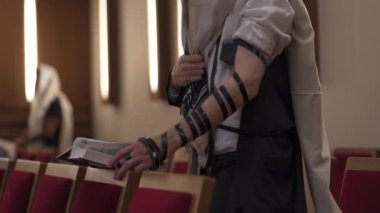 Yetişkin bir adam, bir Yahudi, ayakta kitap okuyor. Dua, tefillin, tallit
