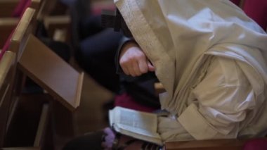 Yetişkin bir adam, bir Yahudi, gözlerini kapatırken bir kitap okur. Dua, tefillin, tallit