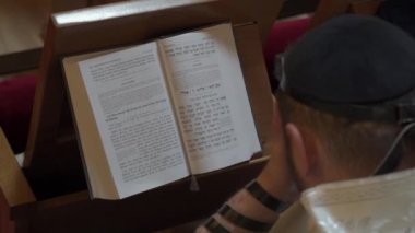 Yetişkin bir adam, bir Yahudi, gözlerini kapatırken bir kitap okur. Dua, tefillin, tallit. Yukarıdan görüntüle