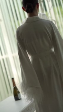 Dikey videolar. Beyaz önlüklü güzel bir kadın gider ve kanepeye oturur. İç çamaşırı giyiyor. Zarif ve seksi görünüyor.