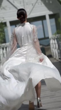 Dikey şarjör. Gelin, güzel bir bornozla, uzun bir trenle, köprü boyunca koşuyor. Ağır çekim