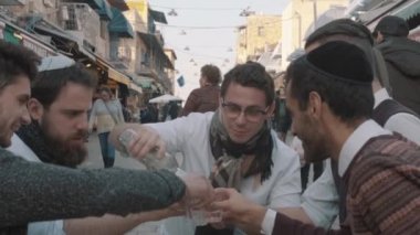 Jerusalem, Israel - February 14, 2022: A group of young Jewish boys celebrate Purim at a market in downtown Jerusalem. The camera moves away. Slo-mo