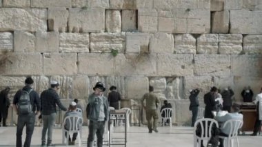 Kudüs, İsrail - 14 Şubat 2022: Batı Duvarı Meydanı. Yahudiler Büyük Ağlama Duvarı 'nın yanında dua ediyorlar. Turistler meydanda yürürken telefonla fotoğraf çekiyorlar.